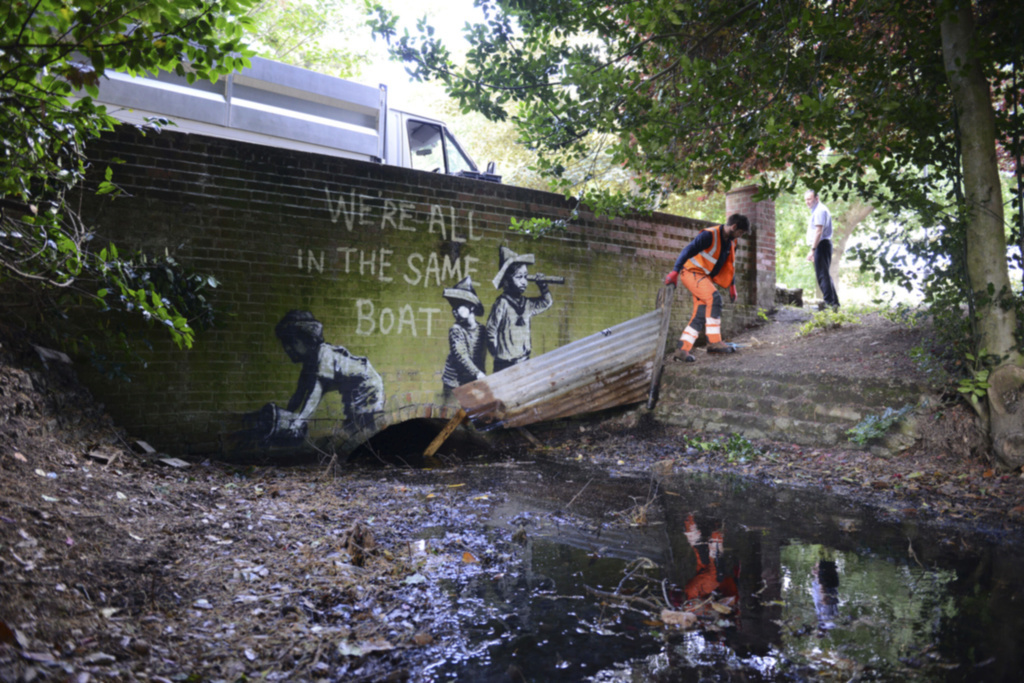Faisant écho à la crise environnementale, une peinture présente trois enfants, dont l'un écope avec un seau, sur une barque de tôle ondulée.
