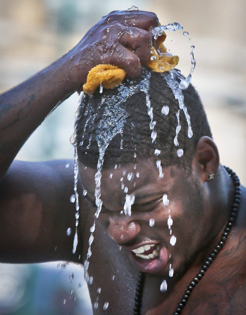 Abass Asali squeeze a soaking rag of water onto his head while selling "ice cold" bottled water on Thursday, July 18, 2013 in Harlem, N.Y.  An excessive heat warning is again in effect as the city hit the high-90s in a fifth day of a heatwave.  (AP Photo/Bebeto Matthews)