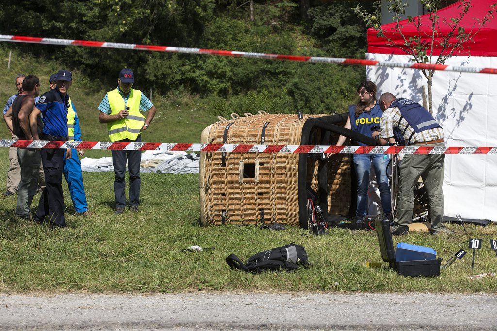 Swiss police officer inspect the gondola of hot air ballon after it crashed, in Montbovon near Chateaux d'Oex, Switzerland, Tuesday,  August 6, 2013. A hot air balloon crashed Tuesday in the region Montbovon in the canton of Fribourg. One of the occupants died and four others were seriously injured. (KEYSTONE/Salvatore Di Nolfi)