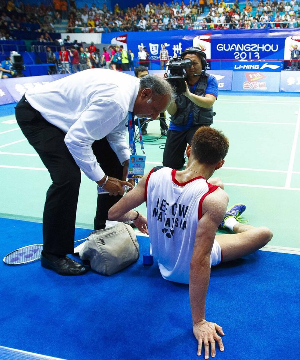 epa03820721 Lee Chong Wei of Malaysia receives medical attention during the men's singles final match against Lin Dan of China on day seven of the 2013 BWF World Championships in Guangzhou, China 11 August 2013.  EPA/MIKE PICKLES