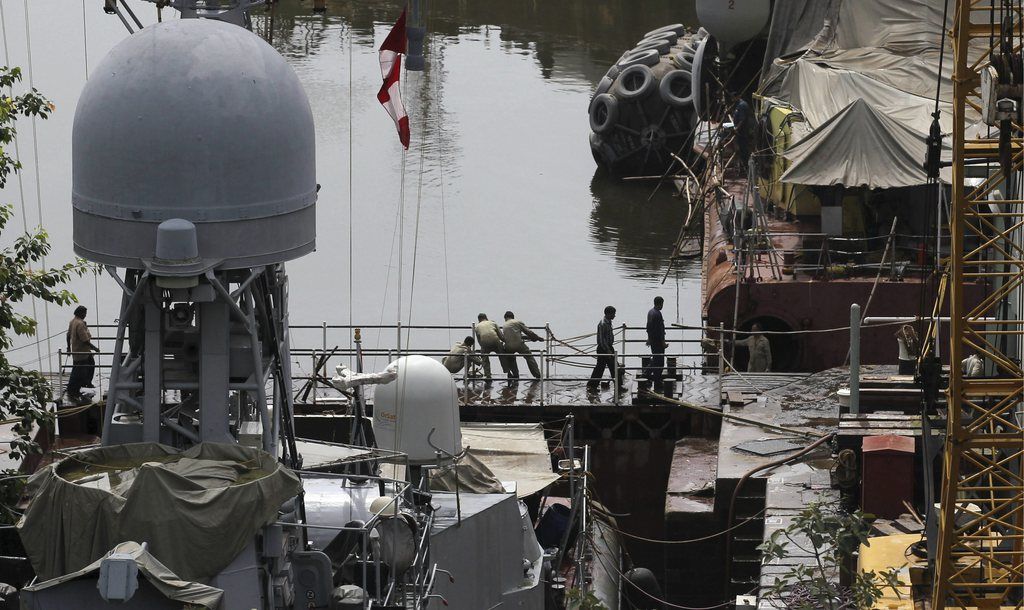 Indian navy sailors work at a naval dockyard where a submarine caught fire and sank after an explosion early Wednesday in Mumbai, India, Wednesday, Aug. 14, 2013. India?s Defense Minister A.K. Antony confirmed loss of lives in a navy submarine explosion at its home port in Mumbai, but gave no details. Eighteen sailors were trapped aboard the submarine, the Indian navy said. (AP Photo/Rafiq Maqbool)