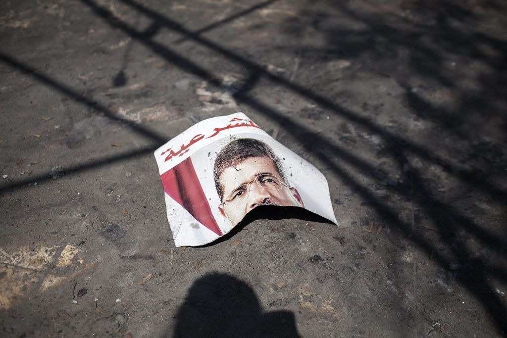 A ripped poster of Egypt's ousted President Mohammed Morsi lies on the ground in the courtyard of the Rabaah Al-Adawiya mosque in Nasr city, Cairo, Egypt, Wednesday, Aug. 21, 2013. Egyptian authorities have arrested two more Islamist figures: a hard-line cleric trying to flee the country across the Libyan border and a spokesman for the Muslim Brotherhood group before leaving for Italy. The arrests are the latest in a crackdown by Egypt's new military-backed leaders against Islamists. (AP Photo/Manu Brabo)