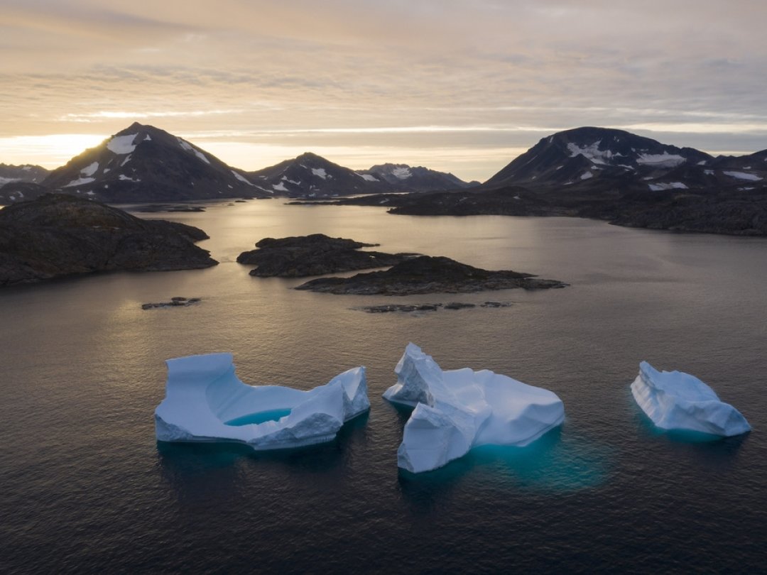 De grands icebergs flottent au loin alors que le soleil se lève près de Kulusuk, au Groenland, le 16 août 2019.