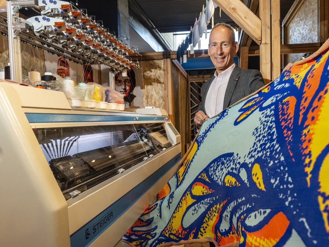 Dans le nouvel espace Innothèque, l’entreprise Steiger présente une machine à tricoter industrielle qui tricote en direct une œuvre d’art monumentale, en partie dévoilée ici par son directeur général Pierre-Yves Bonvin.