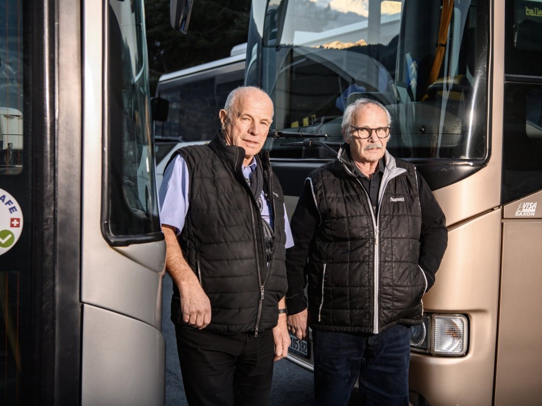 Jean-Mary et Régis Ballestraz, codirecteurs des Cars Ballestraz, posent devant les deux véhicules qui constitueront encore la flotte du transporteur après la fin de leur concession de transport public.
