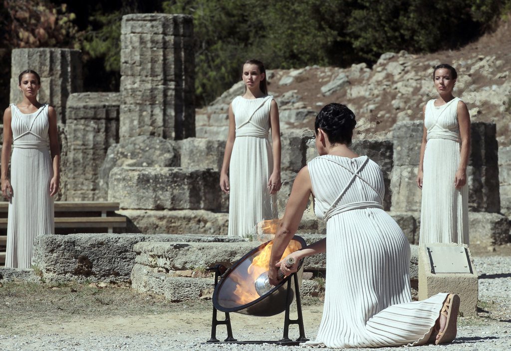 epa03887160 Actress Ino Menegaki (front), in the role of the High Priestess, lights the torch of the Olympic Flame during the rehearsal of the Lighting Ceremony of the Olympic Flame for the Sochi Winter Olympics 2014, in front of the Hera Temple in Ancient Olympia, Greece, 28 September 2013. The flame will make a 56,000km journey through Greece and Russia  using 14,000 torchbearers. It will be handed to Sochi organizers on 05 October 2013 at Athens' Panathinaic Stadium, where the first modern games were held in 1896. The Sochi Games will be held from 07 until 23 February 2014.  EPA/ORESTIS PANAGIOTOU