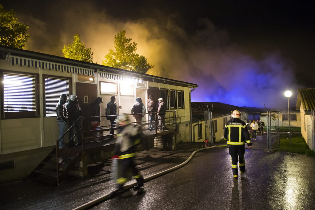Des pompiers travaillent sur l'incendie de d'un pavillon du Foyer de la Poya, un centre pour requérants d'asile déboutés dans la nuit du lundi 14 au mardi 15 octobre à Fribourg. 