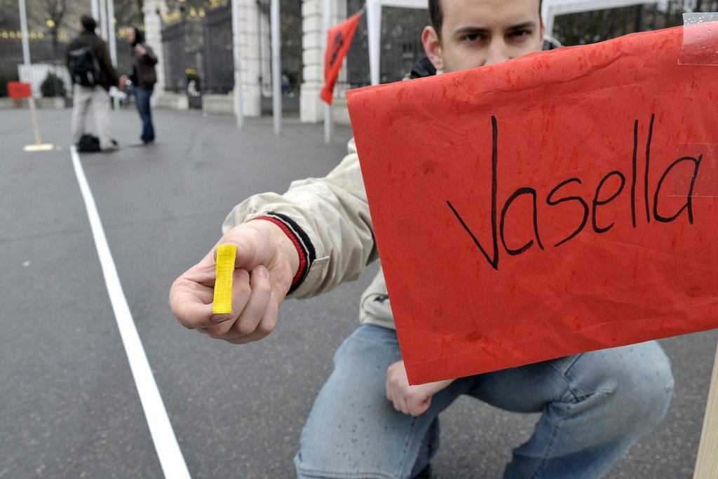 Un jeune socialiste montre en 2010 à Genève un bout de ruban adhésif représentant le salaire d'une personne normale environ 3300 CHF par mois  en comparaison avec celui de Daniel Vasella, ex-CEO de Novartis qui était de 3 300 00 CHF par mois. 