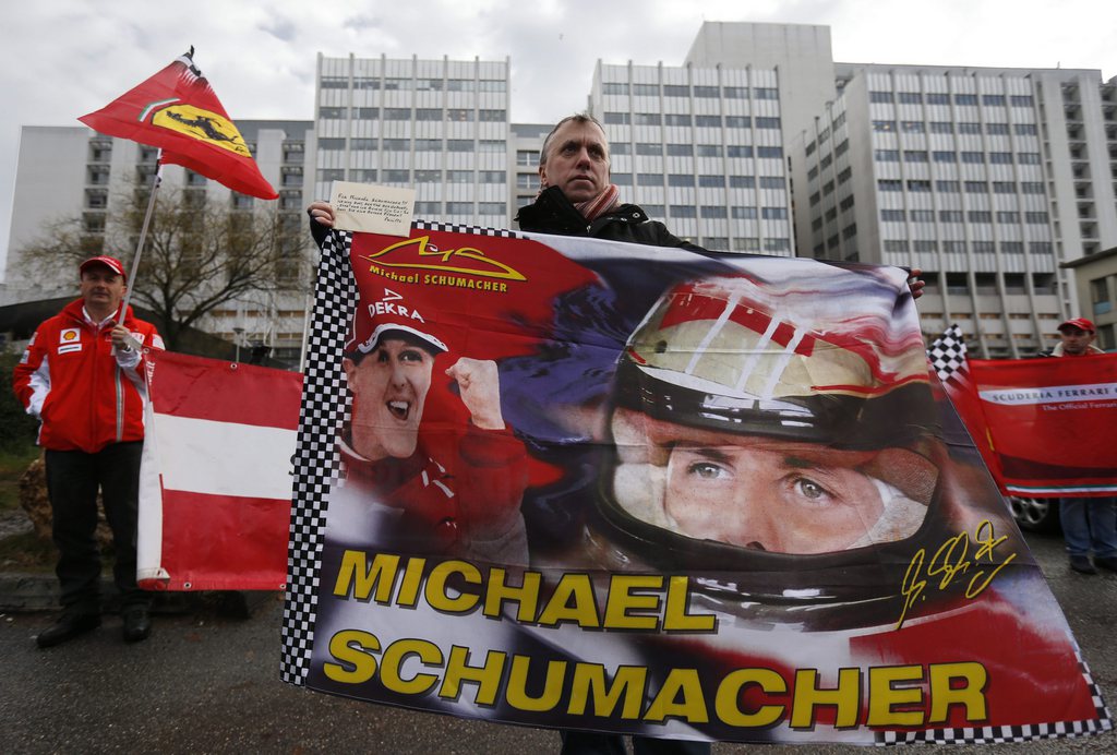epa04006843   On the day of Michael Schumacher's 45th birthday, a Ferrari fan  waves a flag in a vigil  for retired Formula One German racing driver Michael Schumacher outside the 'Centre Hospitalier Universitaire' (CHU) hospital in Grenoble, France, 03 January 2014. Schumacher is still being treated at the  hospital after he was admitted in a coma with a cranial trauma following a ski accident in Meribel.  EPA/GUILLAUME HORCAJUELO