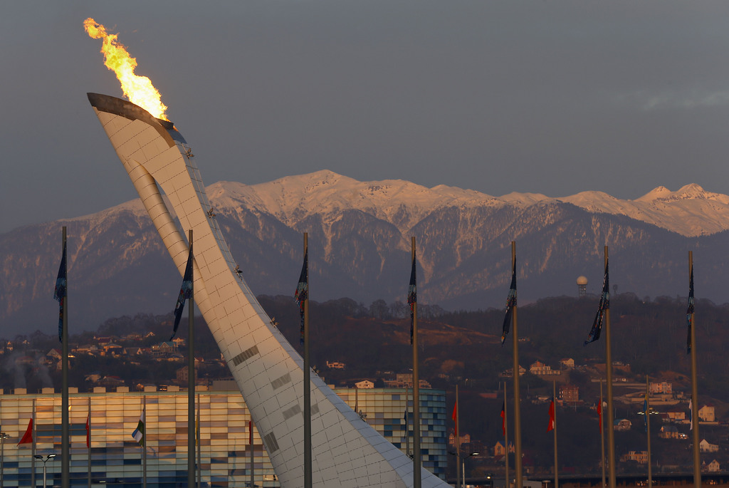 Alpenglo settles on the Caucasus mountains at sunset as the Olympic flame burns above Olympic Park during the 2014 Winter Olympics in Sochi, Russia, Saturday, Feb. 8, 2014. (AP Photo/Julie Jacobson)