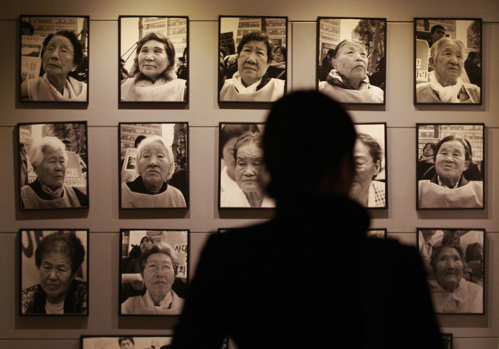 In this Feb. 3. 2014 photo, a visitor looks at portraits of late former comfort women who were forced to serve for the Japanese troops as a sexual slave during World War II, at the House of Sharing, a nursing home and museum for 10 former sex slaves, in Toechon, South Korea. There are only 55 women left who registered with the South Korean government as former sex slaves from the war _ down from a peak of more than 230. Their average age is 88. (AP Photo/Ahn Young-joon)