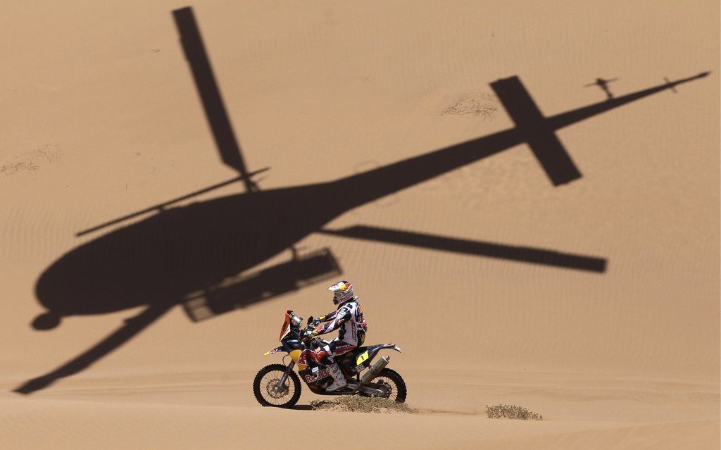 The shadow of a helicopter is projected over KTM rider Cyril Despres of France competes in the 12th stage of the 2013 Dakar Rally from Fiambala, Argentina, to Copiapo, Chile, Thursday, Jan. 17, 2013. The race finishes in Santiago, Chile, on Jan. 20. (AP Photo/Victor R. Caivano)