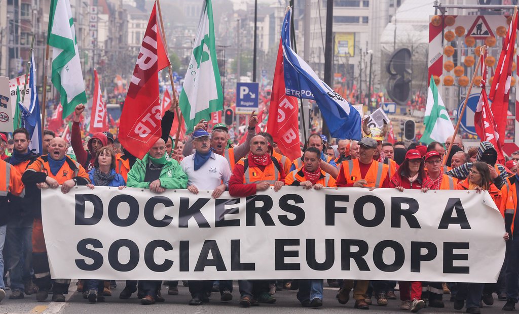 epa04153768 Protesters band together behind a protest banner reading 'Dockers for a social Europe' during a protest called by trade unions in Brussels, Belgium, 04 April 2014. According to media reports, about 40,000 people were to take part in a protest denouncing austerity measures.  EPA/JULIEN WARNAND