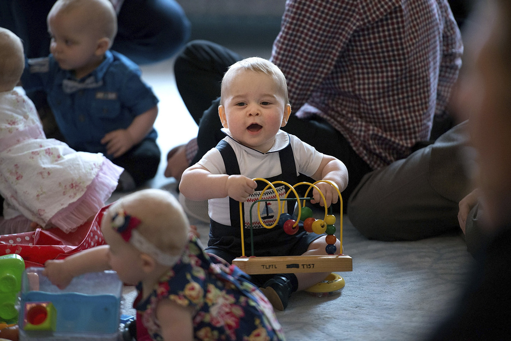 Britain's Prince George, center, plays during a visit to Plunket nurse and parents group at Government House in Wellington, New Zealand, Wednesday, April 9, 2014. Plunket is a national not-for-profit organization that provides care for children and families in New Zealand. Britain's Prince William, his wife Kate, the Duchess of Cambridge and their son, Prince George, are on a three-week tour of New Zealand and Australia. (AP Photo/Marty Melville, Pool)