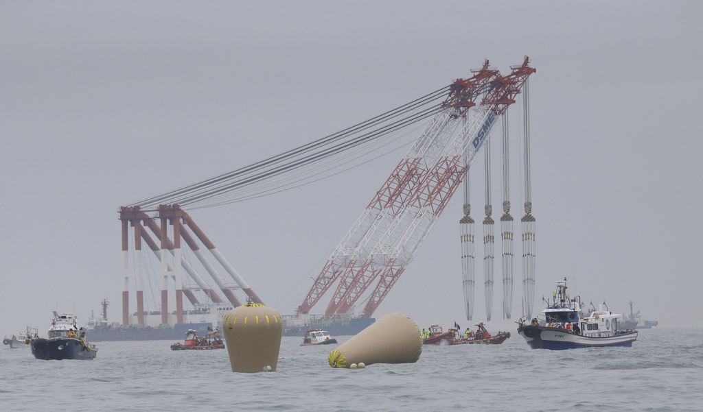 Cranes wait near the buoys installed to mark the sunken 6,852-ton ferry Sewol in the water off the southern coast near Jindo, south of Seoul, South Korea, Friday, April 18, 2014. Rescuers scrambled to find hundreds of ferry passengers still missing Friday and feared dead, as fresh questions emerged about whether quicker action by the captain of the doomed ship could have saved lives. (AP Photo/Lee Jin-man)