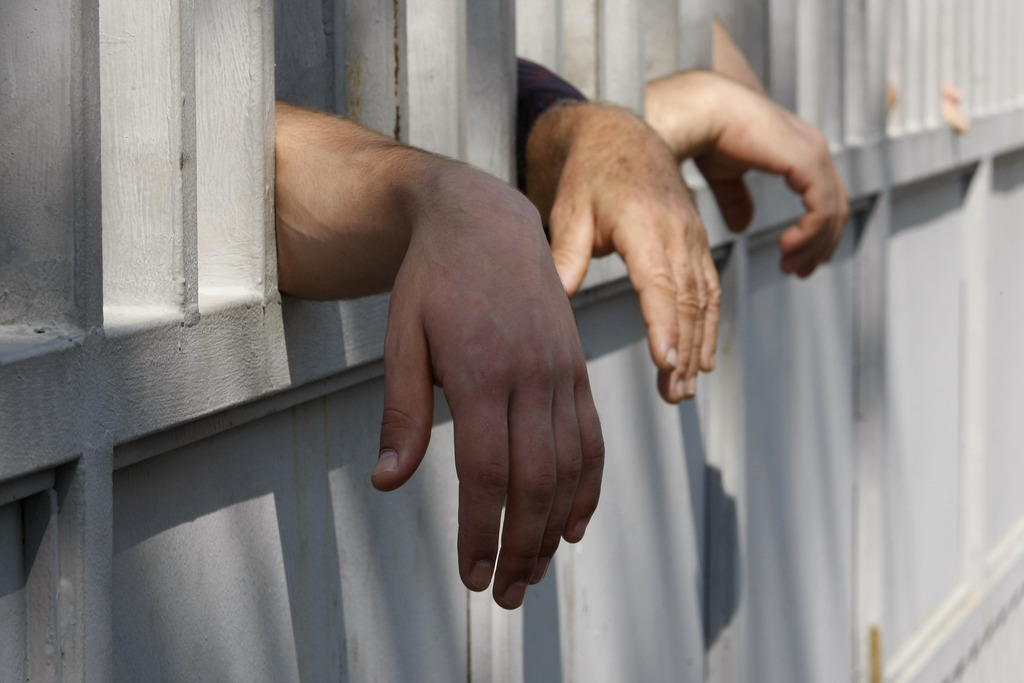 Relatives of inmates reach through a prison fence as they stand to see their family members during a protest rally against prison abuse in Tbilisi, Georgia, Friday, Sept. 21, 2012. Thousands rallied Friday in Georgia to demand the prosecution of top officials fired in a prison abuse scandal that threatens to unseat the governing pro-Western party in the country's Oct. 1 parliamentary election. (AP Photo/Shakh Aivazov)
