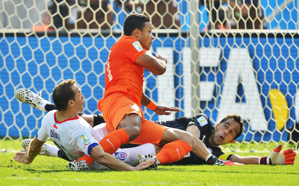 epa04275466 Memphis Depay of the Netherlands (C) and Chile's Marcelo Diaz (L) and goalkeeper Claudio Bravo (R) vie for the ball during the FIFA World Cup 2014 group B preliminary round match between the Netherlands and Chile at the Arena Corinthians in Sao Paulo, Brazil, 23 June 2014. ....(RESTRICTIONS APPLY: Editorial Use Only, not used in association with any commercial entity - Images must not be used in any form of alert service or push service of any kind including via mobile alert services, downloads to mobile devices or MMS messaging - Images must appear as still images and must not emulate match action video footage - No alteration is made to, and no text or image is superimposed over, any published image which: (a) intentionally obscures or removes a sponsor identification image; or (b) adds or overlays the commercial identification of any third party which is not officially associated with the FIFA World Cup)  EPA/KOEN VAN WEEL   EDITORIAL USE ONLY