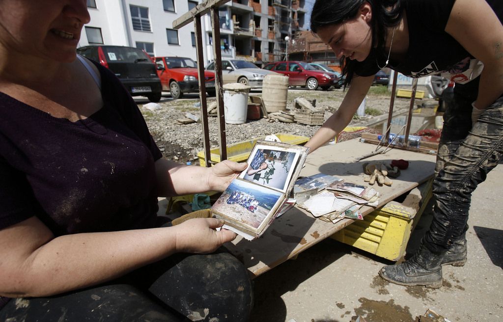 Bosnian women look at family photo albums in front of their home after devastating floods in the Bosnian town of Doboj 120 kms north of the Bosnian capital of Sarajevo, on Thursday, May 22, 2014. Thousands evacuated in Serbia and Bosnia as the emergency services fought with worst floods in a century.(AP Photo/Amel Emric)