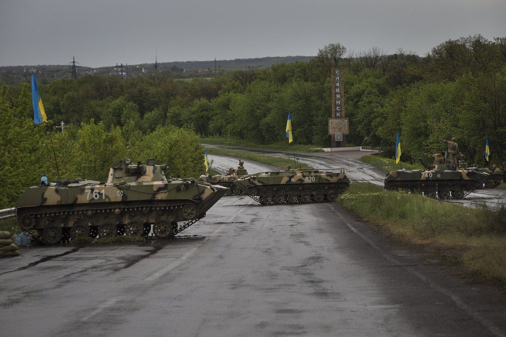 Armored vehicles parked at a Ukrainian army checkpoint on the main road between Kramatorsk and Slovyansk, 10 kilometers (6.2 miles) south of Slovyansk, Ukraine, Thursday, May 8, 2014. The words on the marker in the background read "Slovyansk". Russia has pulled back its troops from the Ukrainian border, Vladimir Putin told diplomats Wednesday as he urged insurgents in southeastern Ukraine to postpone their planned referendum Sunday on autonomy. (AP Photo/Alexander Zemlianichenko)