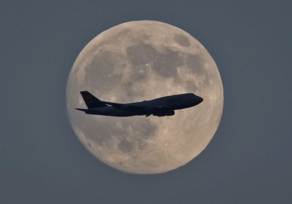 epa03755954 A Jumbo jet is silhoutted against the moon on it's landing flight path to Frankfurt am Main airport, Frankfurt am Main, Germany, 22 June 2013. Reports state on 23 June 2013 the moon will be at its closest point to Earth, called perigee. This relatively close brush will happen as the moon enters its fullest phase, creating the cosmic coincidence known as the supermoon. At its fullest and closest, the moon will appear about 12 per cent larger in the sky.  EPA/FRANK RUMumpenhorst