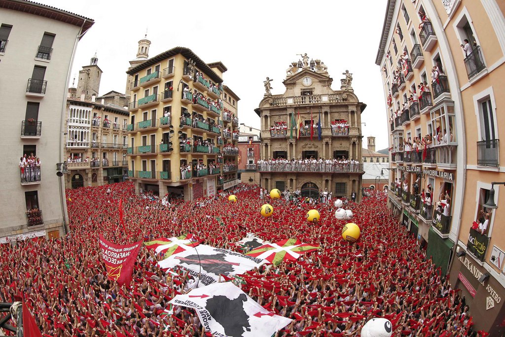 epa04302204 A picture taken with a fish-eye lens shows thousands of revellers holding up their red scarfs as the rocket fire or 'Txupinazo' marks the start of the Festival of San Fermin (or Sanfermines) at Consistorio square in Pamplona, Spain, 06 July 2014. The annual nine day long running-with-the-bulls fiesta commemorates St. Fermin, Pamplona's patron saint.  EPA/JESUS DIGES