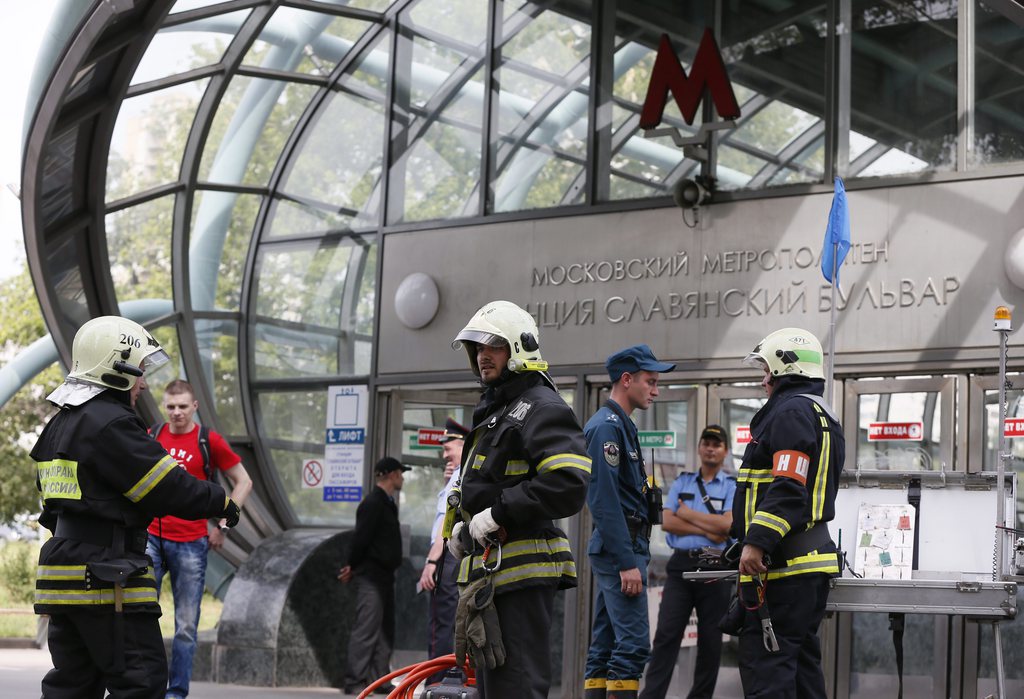 epa04316481 Russian fire fighters and rescuers stand in front of  the 'Slaviansky Boulevard' metro station, near where three carriages derailed underground, in Mocow, Russia, 15 Jul 2014. At least 10 people were killed and more than 100 injured in Moscow when a packed underground train derailed, authorities said. Georgy Golukhov, the head of Moscow's health department, said 106 people were hospitalized and more than half of them were in critical condition, Russian news agencies reported. The accident happened when the train suddenly braked in a tunnel during the morning rush hour. Investigators said the reason was a wrong signal.  EPA/YURI KOCHETKOV