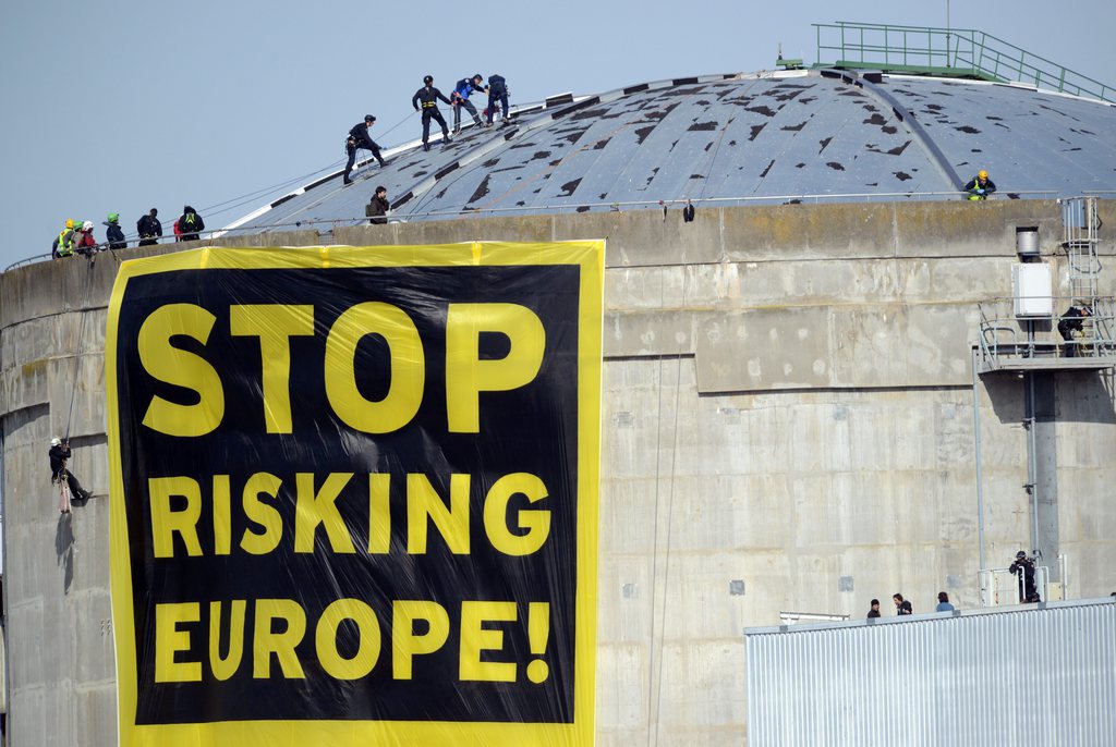 epa04130680 A protest banner from Greenpeace with text reading 'Stop Risking Europe!' is unfurled by activists at the Fessenheim nuclear power plant in Fessenheim, France, 18 March 2014. An estimated 50 activists entered the grounds of the nuclear power plant. The environmental organization says it wants to draw attention to the 'danger of aging nuclear power plants in Europe'.  EPA/PATRICK SEEGER