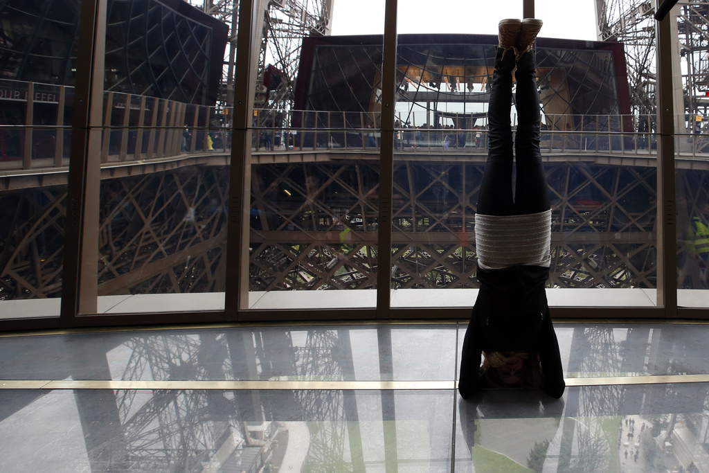 Une visiteuse fait le poirier sur le nouveau plancher de la Tour Eiffel.