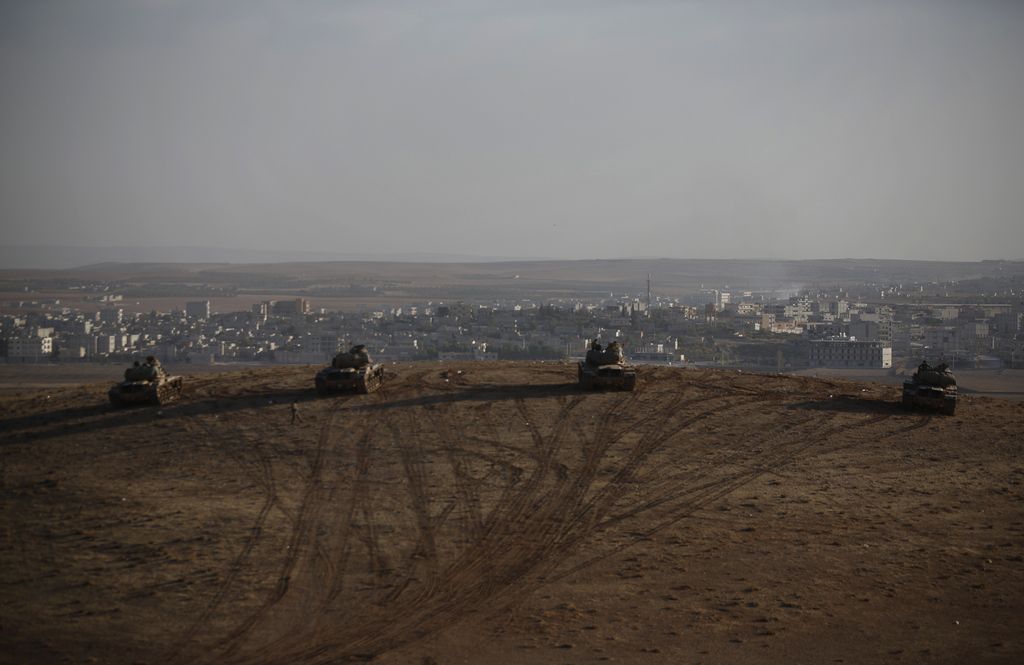 Turkish soldiers hold their positions with their tanks on a hilltop in the outskirts of Suruc, at the Turkey-Syria border, overlooking Kobani, Syria, during fighting between Syrian Kurds and the militants of Islamic State group, Friday, Oct. 10, 2014. Kobani, also known as Ayn Arab, and its surrounding areas, has been under assault by extremists of the Islamic State group since mid-September and is being defended by Kurdish  fighters. (AP Photo/Lefteris Pitarakis)