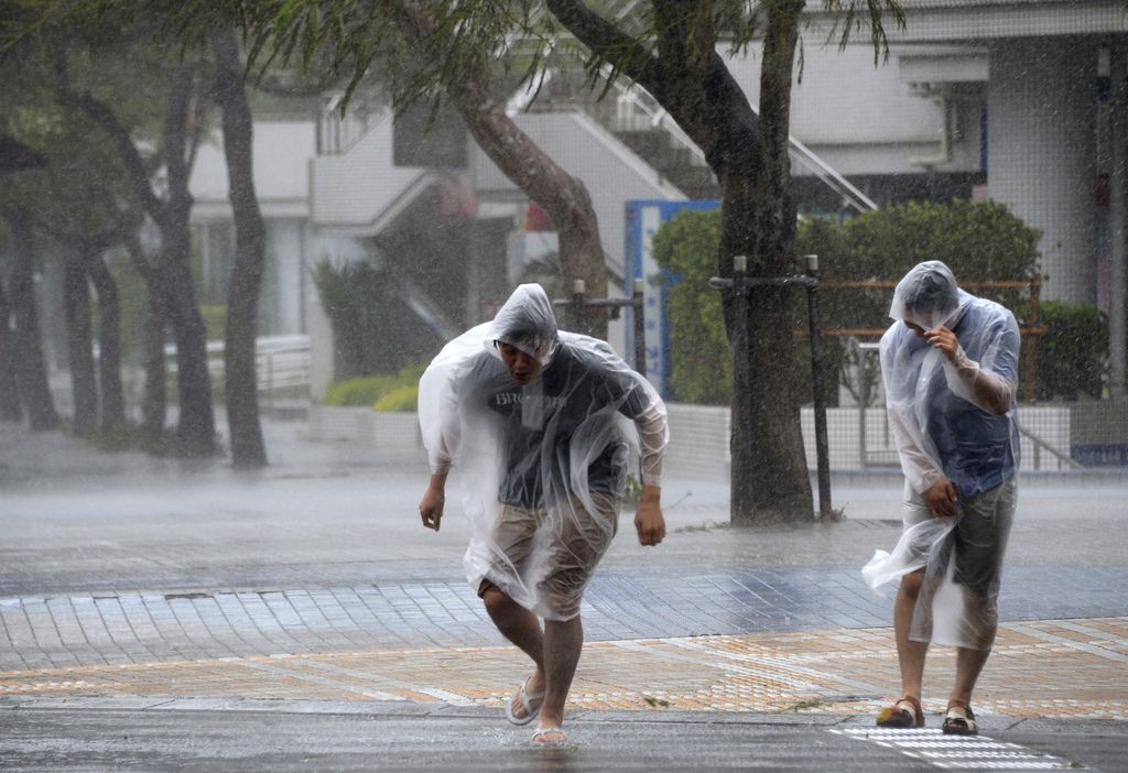 Passersby make their way through strong wind caused by approaching typhoon Vongfong in Naha, Okinawa, southern Japan, Saturday, Oct. 11, 2014.  (AP Photo/Kyodo News) JAPAN OUT, CREDIT MANDATORY