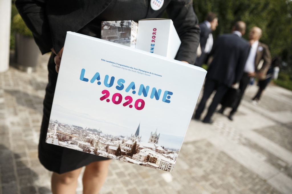 Une membre de l'equipe de Lausanne 2020 pose avec un dossier de candidature de la ville au Jeux olympiques de la Jeunesse 2020 ce mardi 17 juin 2014 devant le siege du Comitee Olympique International (CIO) a Lausanne. (KEYSTONE/Valentin Flauraud)