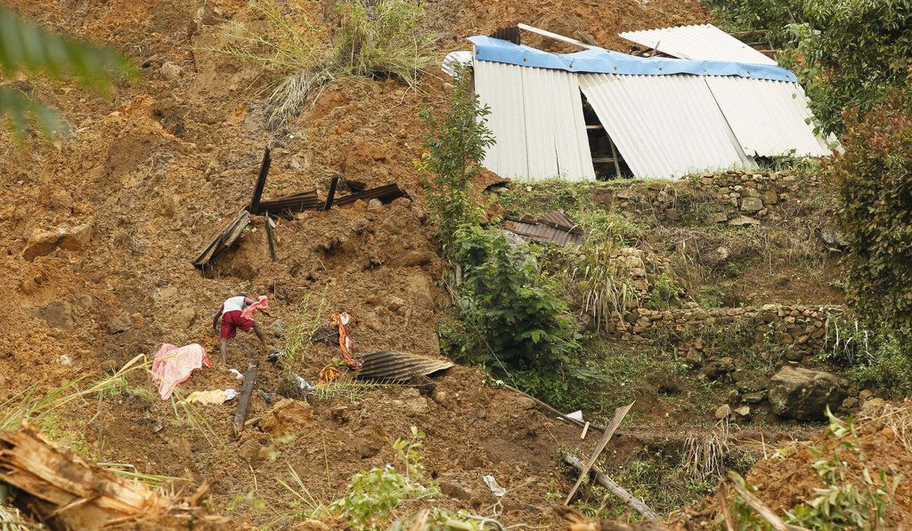 A Sri Lankan man digs the earth with bare hands at the spot where his house stood, looking for his family members,  at the Koslanda tea plantation in Badulla district, about 220 kilometers (140 miles) east of Colombo, Thursday, Oct. 30, 2014. Disaster Management Minister Mahinda Amaraweera estimated the number of dead in Wednesday's disaster at the plantation would be fewer than 100, although villagers said the figure could easily exceed 200. The man was away when the mudslide occurred. (AP Photo/Eranga Jayawardena)