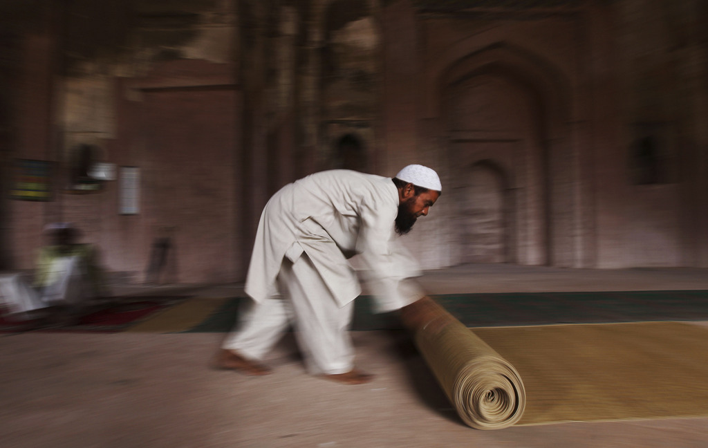 An Indian Muslim rolls a prayer mat at the end of prayers on the first Friday of the holy month of Ramadan at an old Mughal era mosque in New Delhi, India, Friday, July 12, 2013. Muslims throughout the world are celebrating the holy fasting month of Ramadan, refraining from eating, drinking, and smoking from dawn to dusk. (AP Photo/Altaf Qadri)