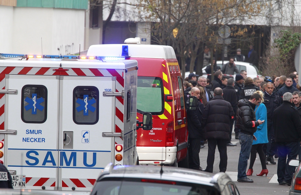 Police officers and rescue workers gather at the scene after gunmen stormed a French newspaper, killing at least 12 people, in Paris, France, Wednesday, Jan. 7, 2015. .Masked gunmen shouting "Allahu akbar!" stormed the Paris offices of the satirical newspaper Charlie Hebdo, killing 12 people, including the paper's editor and a cartoonist, before escaping in a getaway car. It was France's deadliest terror attack in at least two decades. (AP Photo/Remy de la Mauviniere)