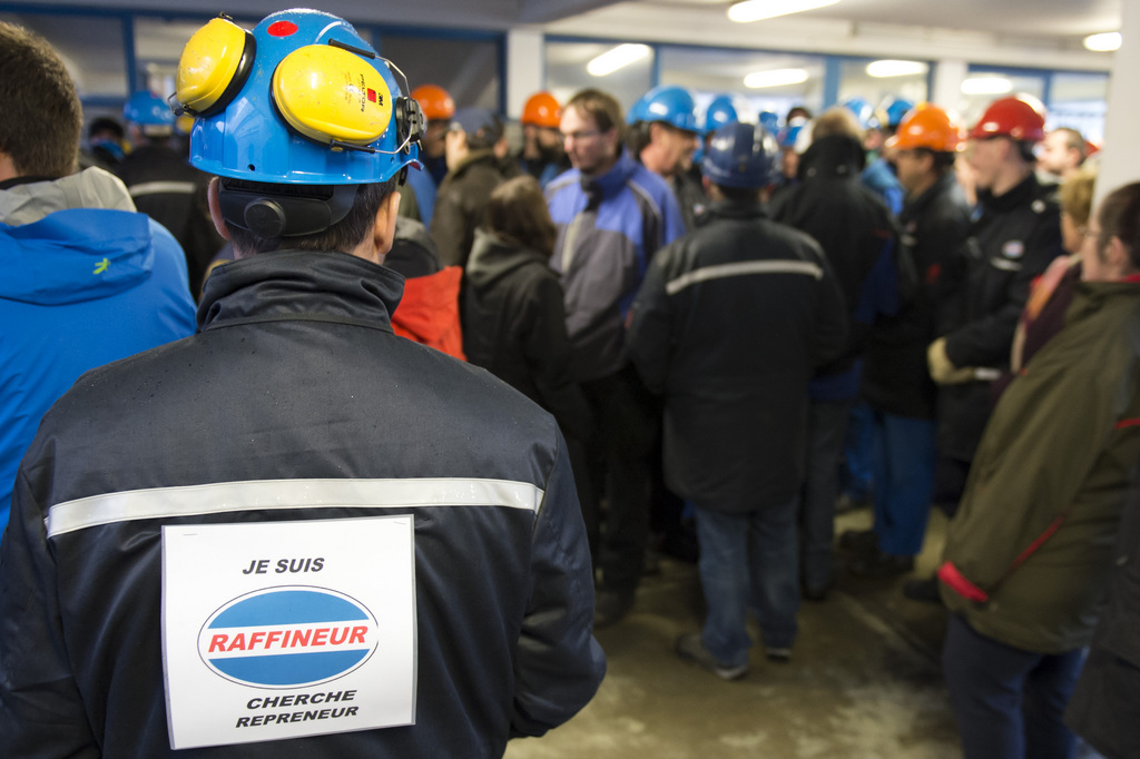 Un employe de la raffinerie Tamoil pose avec une affiche sur sa veste, devant la raffinerie Tamoil avant de faire une haie lors de l'arrivee des dirigeant de Tamoil, ce jeudi 29 janvier 2014 a Collombey. (KEYSTONE/Maxime Schmid)..