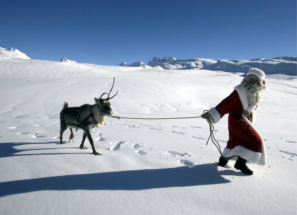 Ein Weihnachtsmann zieht mit seinem Rentier  durch die Schneelandschaft der Melchsee-Frutt im Kanton Obwalden, am Dienstag, 23. Dezember 2008. Ob der Weihnachtsmann zur Arbeit geht oder von der Arbeit kommt bleibt unklar. (KEYSTONE/Urs Flueeler)