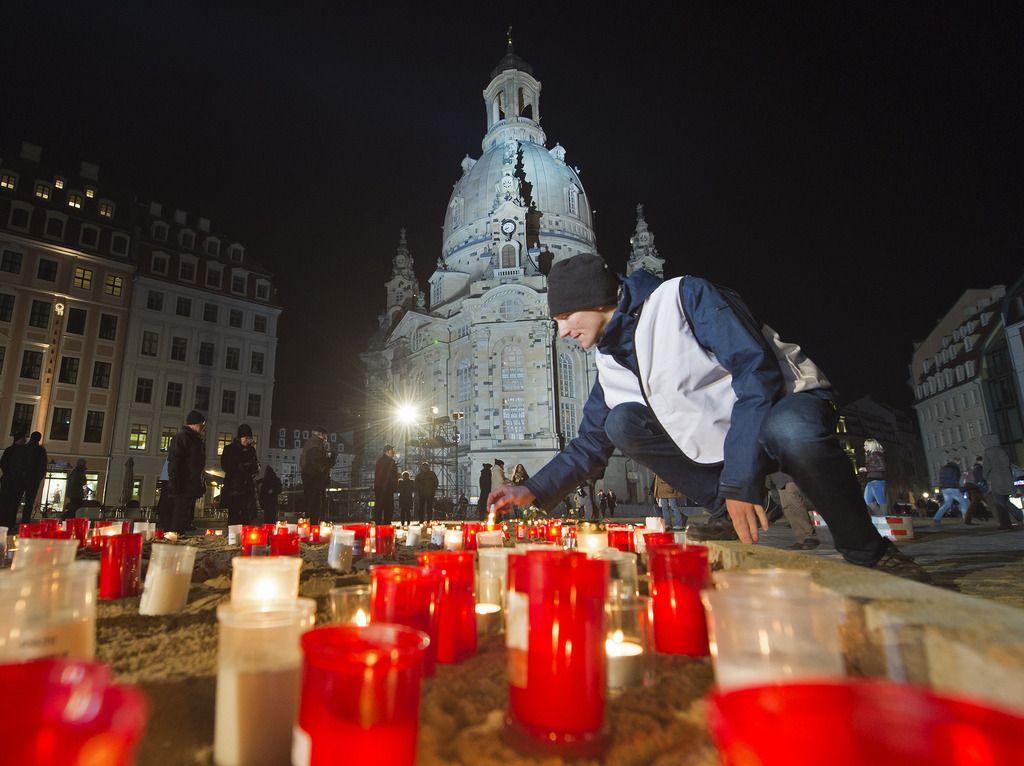 A man lights a candle in front of the Frauenkirche cathedral (Church of Our Lady) commemorating the 70th anniversary of the deadly Allied bombing of Dresden during WWII in Dresden, eastern Germany, Friday, Feb. 13, 2015. British and U.S. bombers on Feb. 13-14, 1945 destroyed Dresden's centuries-old baroque city center. (AP Photo/Jens Meyer)
