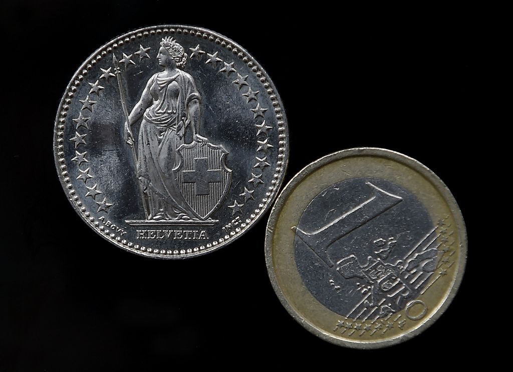 A Euro coin, right, and a Swiss Franc coin  have been placed on a table to be photographed in Gelsenkirchen, Germany, Thursday, Jan. 15, 2015. The European currency has  lost value after Switzerland's central bank said Thursday it has scrapped a policy that limited how much the euro could fall against the Swiss franc, an unexpected decision that caused gyrations in financial markets. (AP Photo/Martin Meissner)