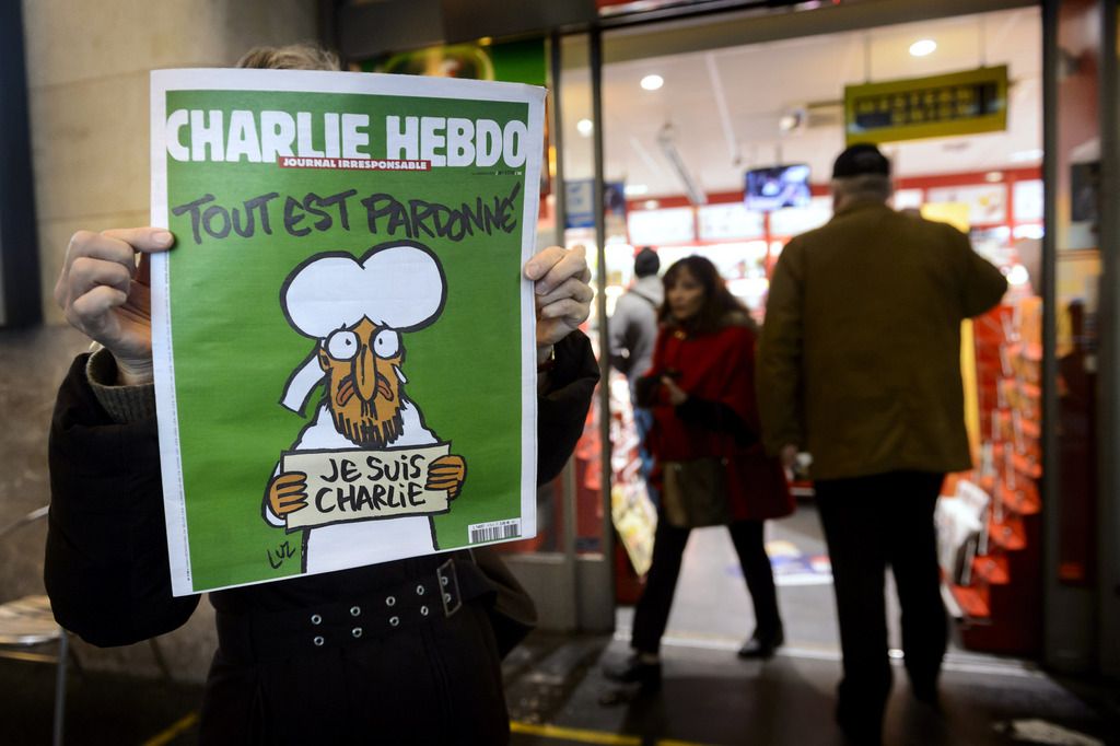 People shows the front page of French satirical magazine Charlie Hebdo in front of a newsstand in Lausanne, Switzerland, early Thursday, January 15, 2015. In an emotional act of defiance, Charlie Hebdo resurrected its irreverent and often provocative newspaper, featuring a caricature of the Prophet Muhammad on the cover that drew immediate criticism and threats of more violence after the 07 January Islamist attacks in Paris. (KEYSTONE/Laurent Gillieron)