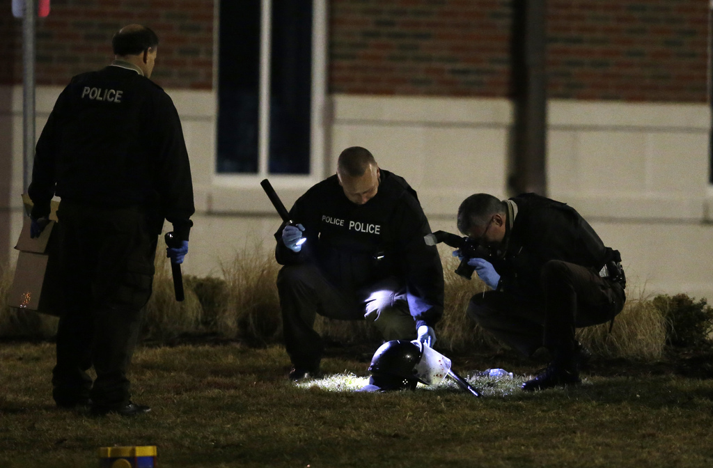 Police shine a light on and photograph a helmet as they investigate the scene where two police officers were shot outside the Ferguson Police Department Thursday, March 12, 2015, in Ferguson, Mo. (AP Photo/Jeff Roberson)