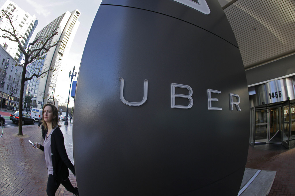FILE--In this file photo taken, Dec. 16, 2014, a woman leaves the headquarters of Uber in San Francisco, Calif.  The Portland, Ore., City Council is expected to OK allowing Uber to operate legally while removing fare limits for traditional taxi companies with Uber drivers getting background checks and insurance. (AP Photo/Eric Risberg, file)