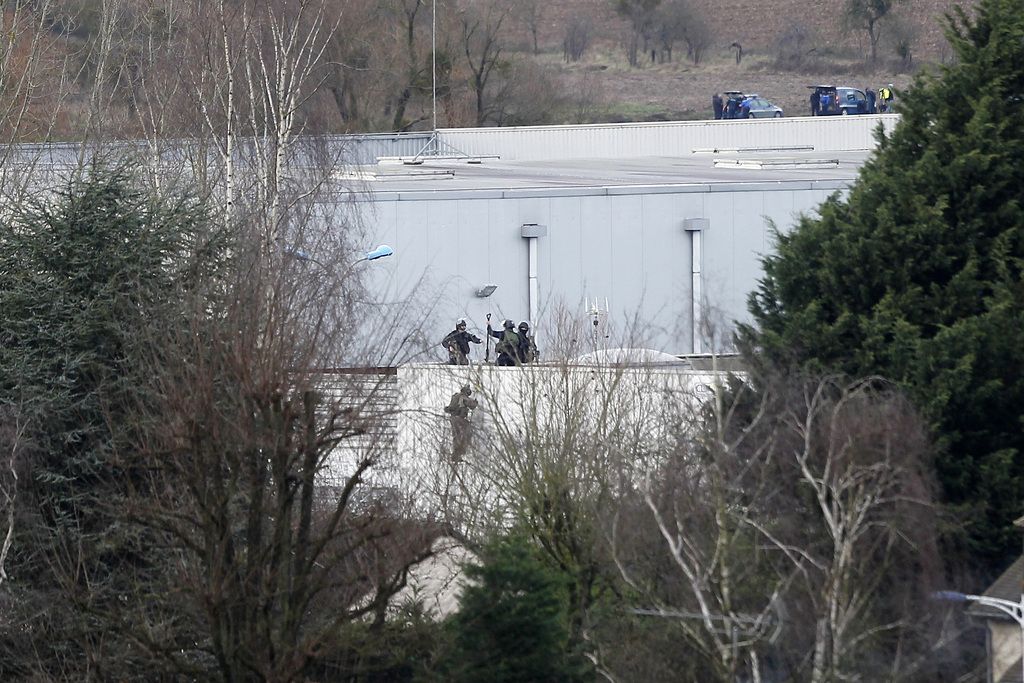Police officers take position atop a building in Dammartin-en-Goele, northeast of Paris, where the two brothers suspected in a deadly terror attack were cornered, Friday, Jan. 9, 2015. Two sets of attackers seized hostages and locked down hundreds of French security forces around the capital on Friday, sending the city into fear and turmoil for a third day in a series of linked attacks that began with the deadly newspaper terror attack that left 12 people dead. (AP Photo/Michel Spingler)