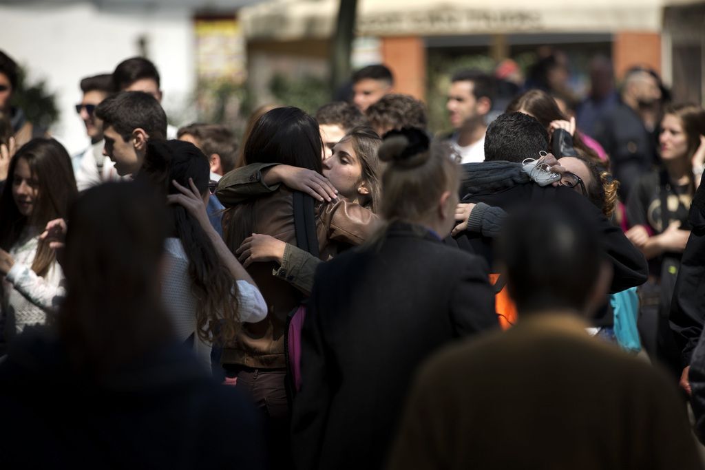 EDS NOTE : SPANISH LAW REQUIRES THAT THE FACES OF MINORS ARE MASKED IN PUBLICATIONS WITHIN SPAIN. People gather outside the high school in Barcelona, Spain, Monday, April 20, 2015. A student walked into the Barcelona school Monday morning and killed a teacher and wounded several other high school students on the 16th anniversary of the massacre of students in shootings at Columbine High School in the U.S. state of Colorado. (AP Photo/Emilio Morenatti)