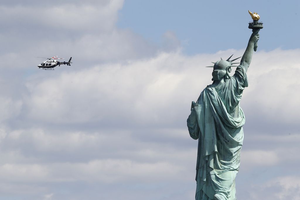 A New York Police helicopter circles over  Liberty Island where the Statue of Liberty was evacuated with officers responding to a report of a suspicious package seen from Jersey City, N.J., Friday, April 24, 2015. Visitors are posting photos online showing hundreds of people being herded toward a ferry landing. Tourists say they were taken off boats while trying to leave nearby Ellis Island. Those vessels then were used to evacuate Liberty Island. (AP Photo/Julio Cortez)