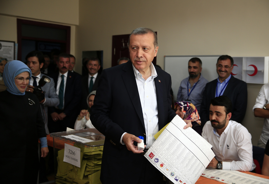 Turkey?s President Recep Tayyip Erdogan, centre, accompanied by his wife Emine, left, holds his ballot as he prepares to vote at a polling station in Istanbul, Turkey, Sunday, June 7, 2015. Turks are heading to the polls in a crucial parliamentary election that will determine whether ruling party lawmakers can rewrite the constitution to bolster the powers of Erdogan. All eyes will be on the results for the main Kurdish party, the Kurdish Peoples' Democratic Party, (HDP). If it crosses a 10 percent threshold for entering parliament as a party, that would extinguish AKP's constitutional plans. (AP Photo/Lefteris Pitarakis}
