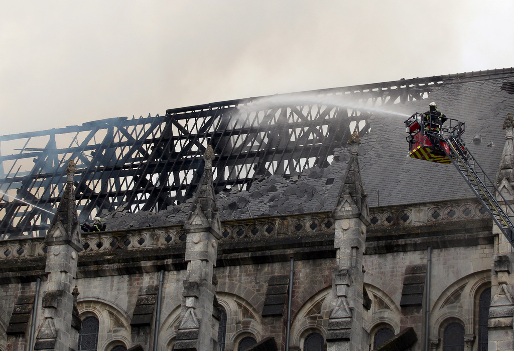 Firefighters hose water to put out the fire in a basilica in Nantes, western France, Monday, June 15, 2015. A fire is ravaging a 19th century basilica in the western French city of Nantes, and has left just a shell of the rooftop. The fire began just after morning Mass on Monday and everyone inside was quickly evacuated, the Rev. Benoit Bertrand of the Nantes diocese told BFM television. (AP Photo/Laetitia Notarianni)