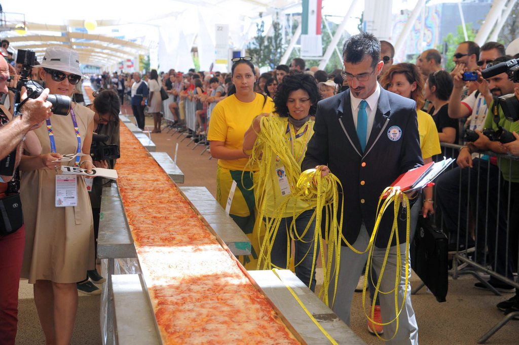 epa04810488 Guinness World Records judge Lorenzo Veltri (R) evaluates a massive pizza during a Guinness World Records attempt for the world's longest pizza during the Expo Milano 2015, in Milan, Italy, 20 June 2015. Some 60 pizza-makers from all over Italy came together to make the world's longest pizza margherita, with a lenght of 1,5 km, for an entry into the Guinness World Records Book, on the occasion of the Tomato Week. The exhibition runs from 01 May to 31 October. This will be the second time Milan hosts the Expo, the first Milan International Exposition took place in 1906. The event's 2015 theme is 'Feeding the Planet, Energy for Life'.  EPA/DANIELE MASCOLO