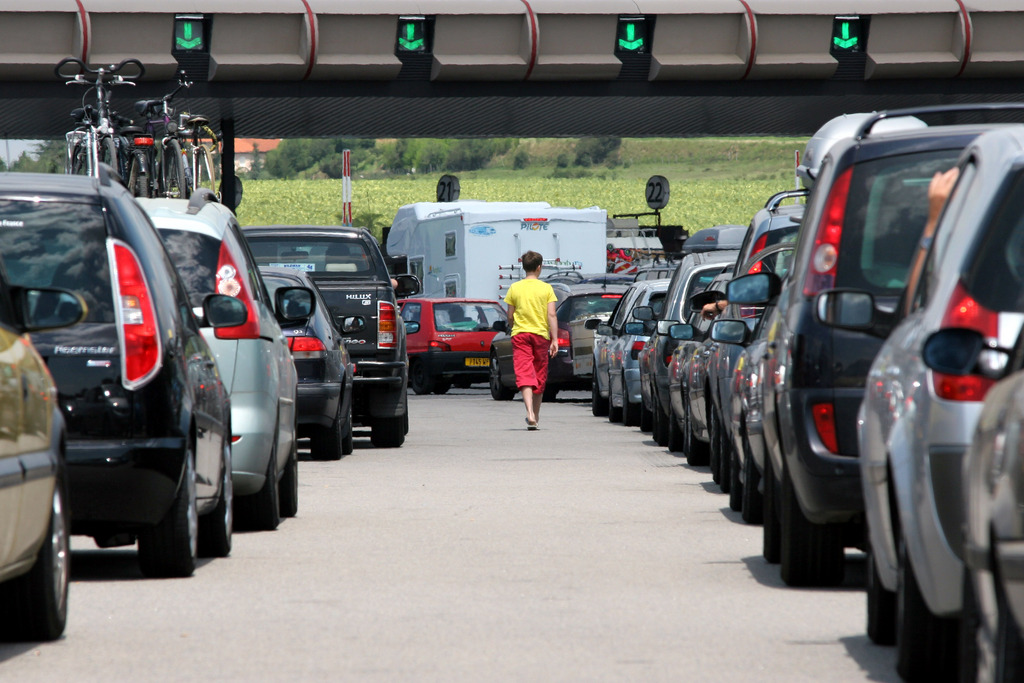 A woman walks between cars queuing at a toll gate on the Autoroute du Soleil, the highway to the south of France and Spain, outside  Vienne, central France, Saturday, July 28, 2007.  Traffic volumes pick up on the busiest day of the year when many people go on holidays. (AP Photo/Laurent Cipriani)