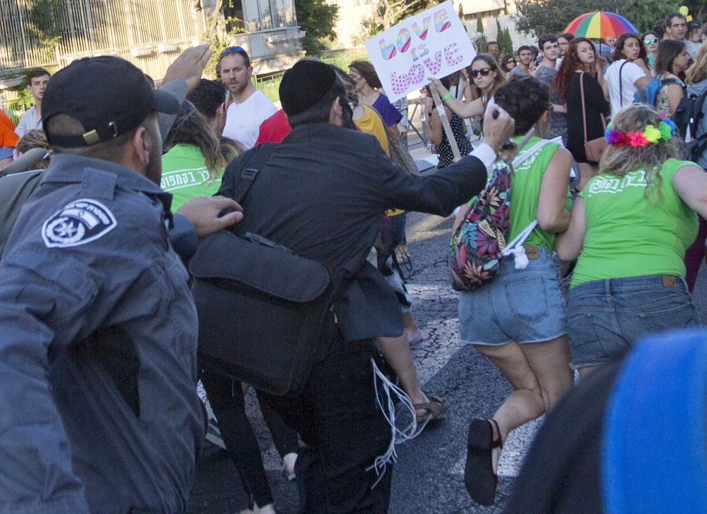 An ultra-Orthodox Jew stabs a woman in the back with a  knife during a Gay Pride parade Thursday, July 30, 2015 in central Jerusalem. Israeli police said several people were stabbed. (AP Photo/Sebastian Scheiner)