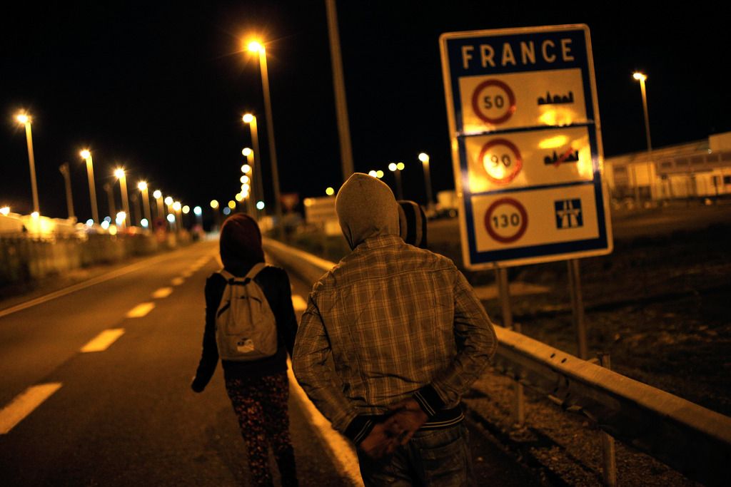 Migrants walk on a road outside the Eurotunnel area, in Calais, northern France, Wednesday, July 29, 2015. About 2,100 migrants tried to storm the area surrounding the Eurotunnel early Tuesday before being repelled by police, an official in the northern French port of Calais said. (AP Photo/Thibault Camus)